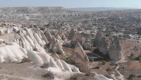 amplia vista aérea ascendente de las increíbles formaciones rocosas en los profundos valles de capadocia, turquía, con casas, templos y ciudades talladas en los muros y pilares de piedra.