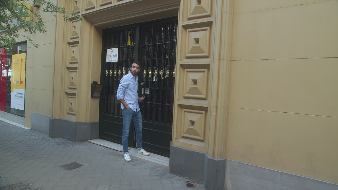 hermosa foto en cámara lenta de un joven latino saliendo del edificio para caminar por una calle en madrid por la tarde