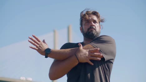 strong hispanic man stretching arms, working out outdoors.