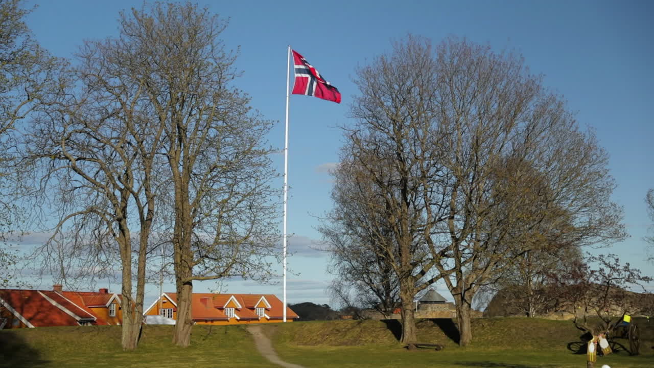 The Norwegian flag on a flagpole being blown by the wind during a clear blue sky, at Fredriksvern verft (Stavern Fort). Stavern, Norway