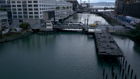a series of images showing a calm body of water, a decaying pier, and a bridge with urban buildings under an overcast sky