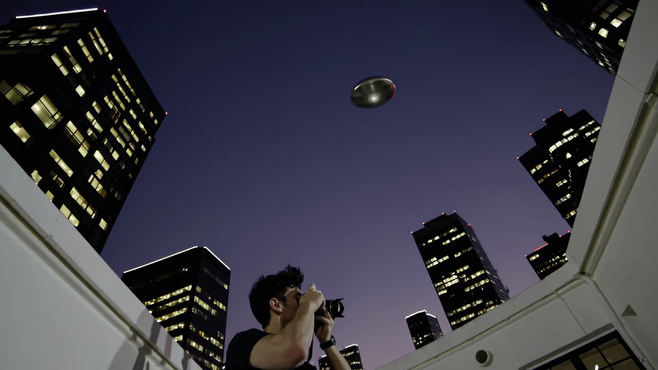 사진작가 가 밤 에 도시 위 에 있는 ufo 를 포착 하고 있다