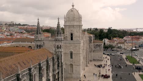 close-up revealing parallax shot of people walking past the jerónimos monastery