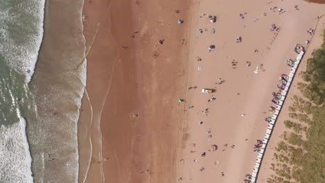 aerial flyover of beach huts on a golden sandy beach