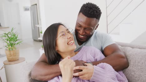 Retrato-De-Una-Feliz-Pareja-Diversa-Abrazándose-En-La-Sala-De-Estar