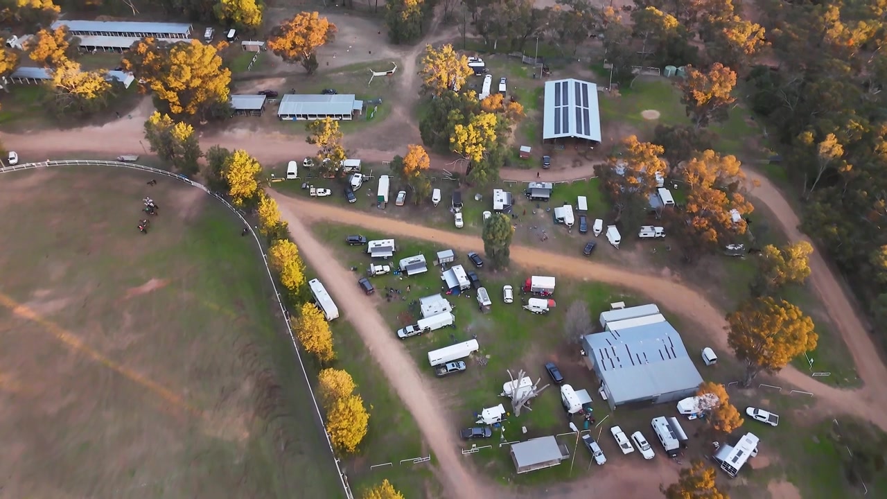 Tomada aérea de drone sobrevoando um recinto de feiras rural e um acampamento em Coonabarabran, Austrália
