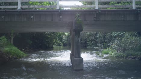 a flowing river under vehicle bridge in tropical suburban australia. clip 5