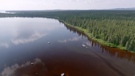 Eine-Breite-Luftaufnahme-Zeigt-Ein-Boot,-Das-Am-Ufer-Eines-Wunderschönen-Kanadischen-Sees-Entlangfährt