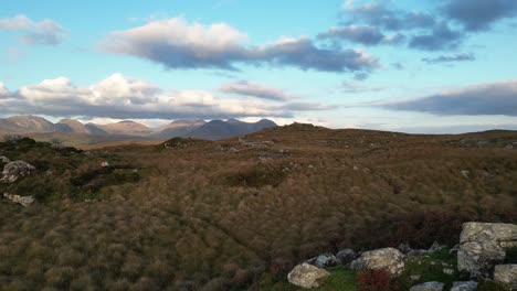 tomada de drones de los lagos de connemara con rocas y lagos tranquilos en primer plano y la cordillera de beanna beola en la distancia, tomando una toma aérea