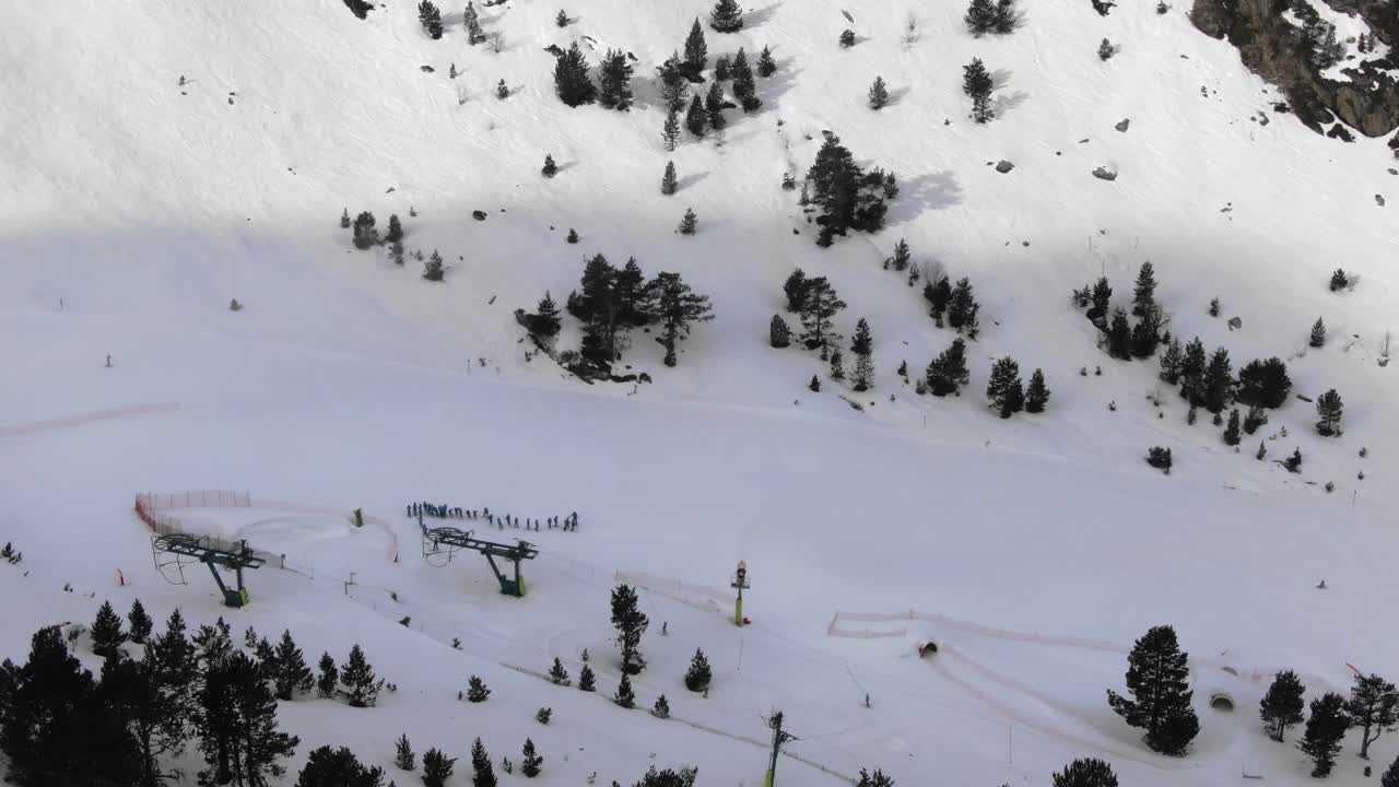 Aerial view of ski lift base with skiers on snowy slope, Ordino Arcalis resort, Andorra