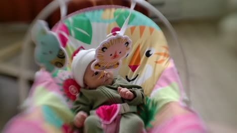 baby lying in colourful bouncer with cute animals - selective focus