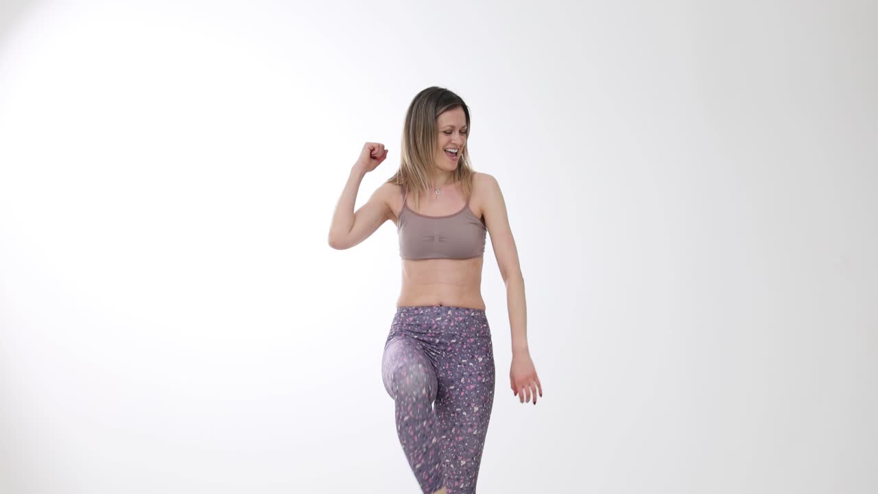 Donna felice che balla e si allena in abbigliamento sportivo su sfondo bianco