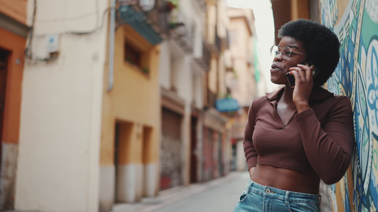 안경을 입은 아프리카 소녀가 거리에서 드폰으로 얘기하고 있다.