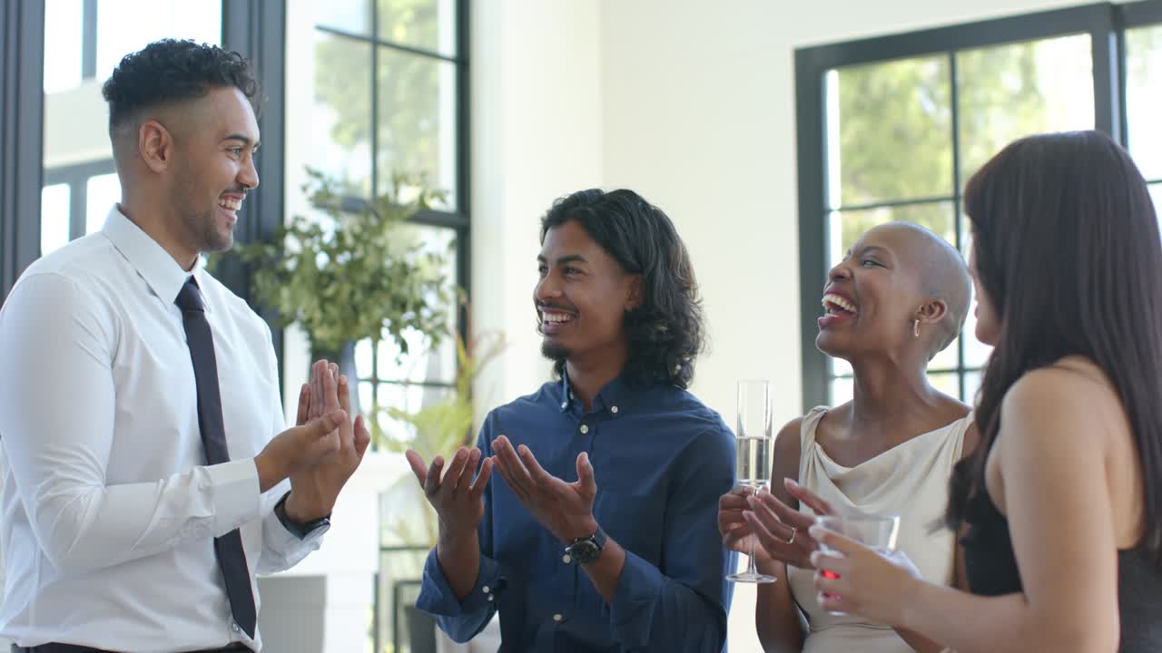 African American friends watching man in white shirt, tie toasting with flutes in loft, copy space
