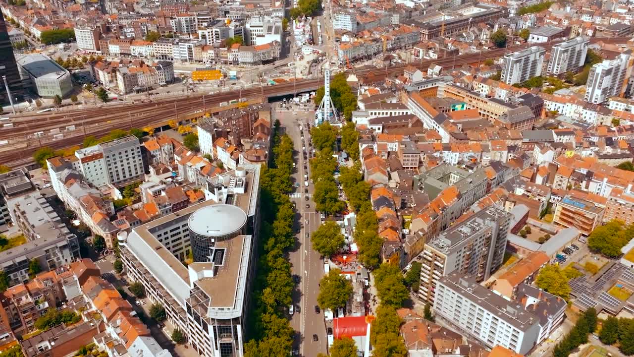 Aerial drone footage flying over Brussels Belgium central city where red rooftops with medieval buildings and Midi railroad station traintracks visible during sunny day in Europe historic city.