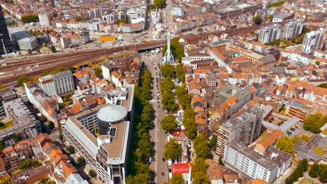 aerial drone footage flying over brussels belgium central city where red rooftops with medieval buildings and midi railroad station traintracks visible during sunny day in europe historic city.
