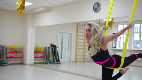 la chica está involucrada en aero yoga en el estudio blanco volando sobre el piso en los lienzos en cámara lenta