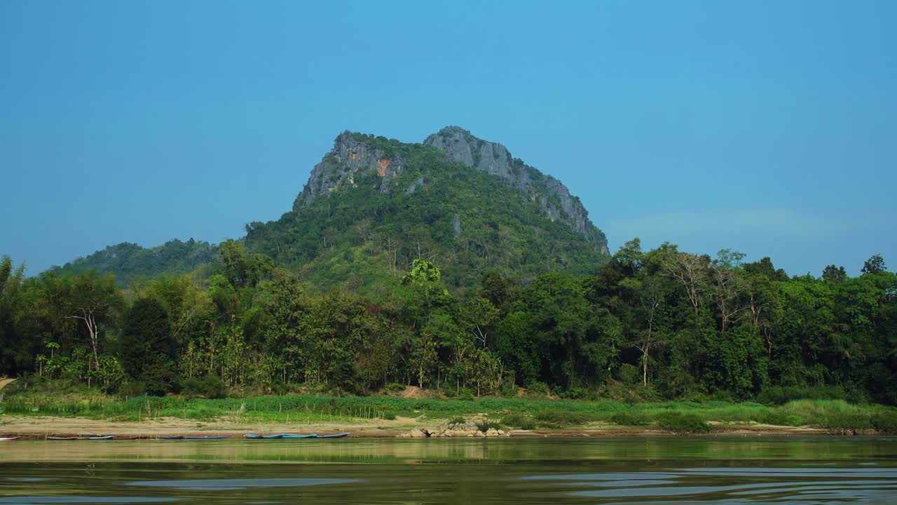 Mountain across a traditional boat tour in Mekong River in Laos in SouthEast Asia