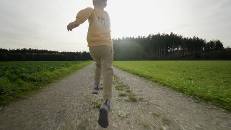 Embrace-the-magic-of-autumn-as-a-playful-boy-runs-toward-the-enchanting-forest-at-sunset