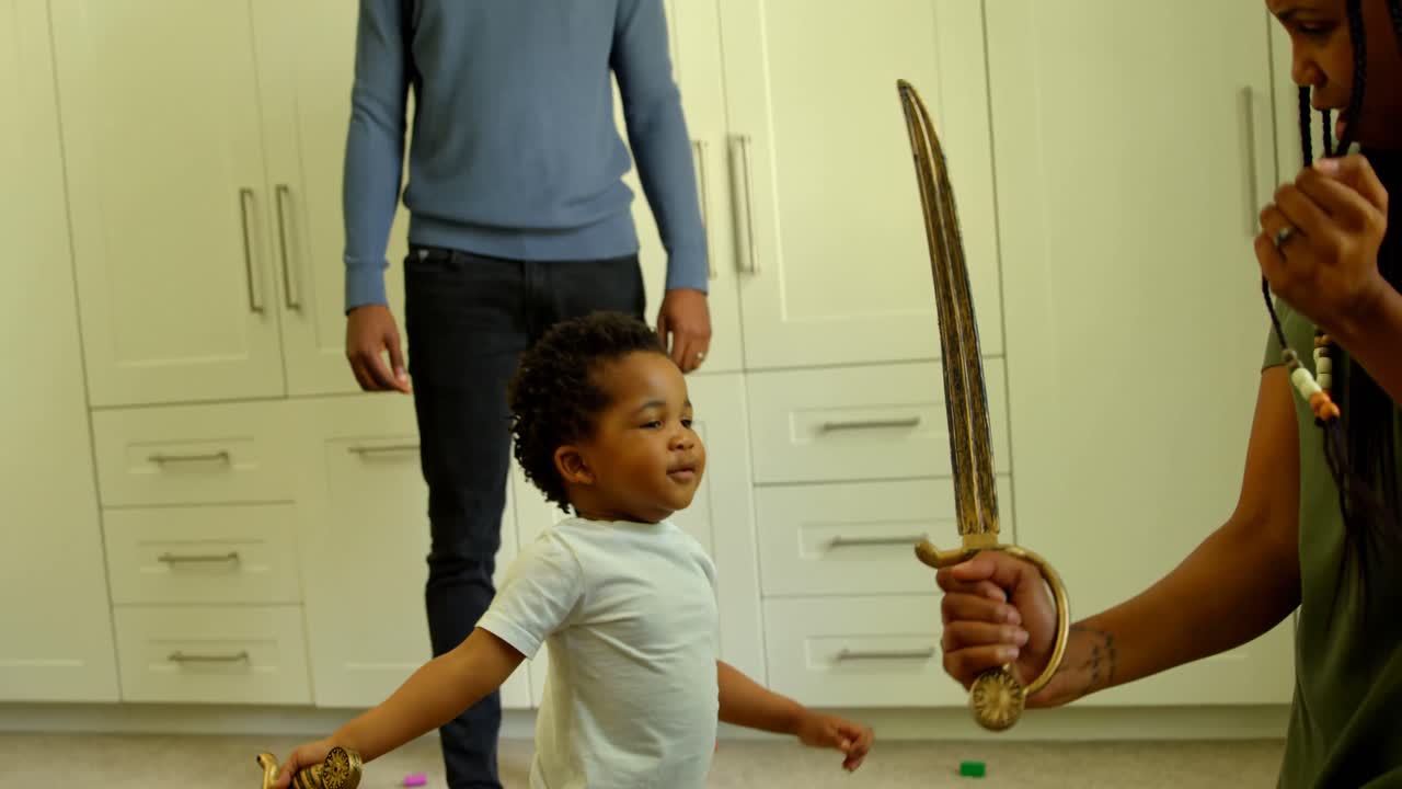 Side view of young black mother and son playing with toy sword in a comfortable home 4k