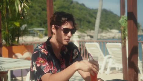 man sitting with drink looking around enjoying atmosphere in restaurant with sea view