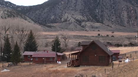 a rural homestead sits at the foot of a mountain range