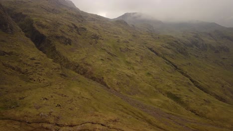 Hombre-Saltando-Sobre-Una-Roca-Y-Viendo-La-Cordillera-De-Inglaterra-En-Un-Día-Nublado