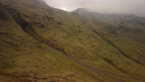 Man-Jumping-on-Rock-and-Viewing-England-Mountain-Range-on-Overcast-Day