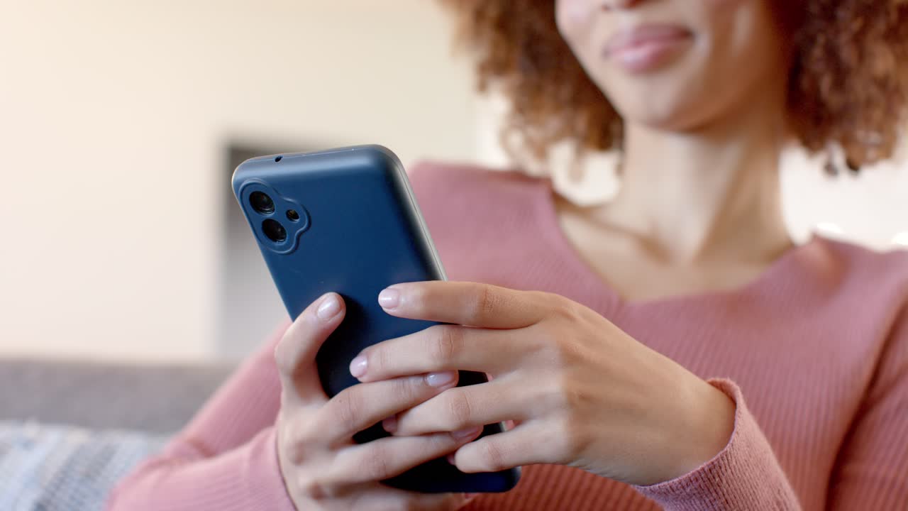Con lo smartphone in mano, una donna scorre il feed sul divano grigio in soggiorno