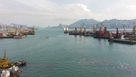 converting an old runway strip into a housing and business district at kai tak downtown hong kong, with vast infrastructure development land and an underwater tunnel laying operation, aerial view.