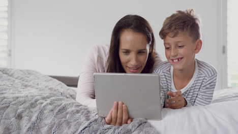 madre y hijo usando tableta digital en el dormitorio en casa 4k