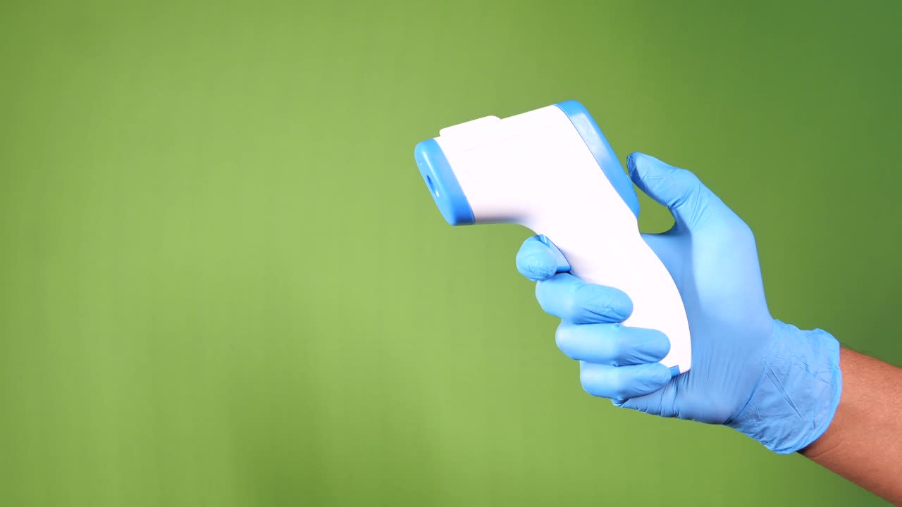 con la mano un termómetro infrarrojo para medir la temperatura.