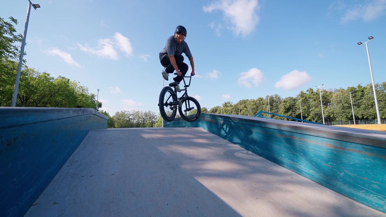 Ung mand springer på BMX-cykel på en rampe i en skatepark