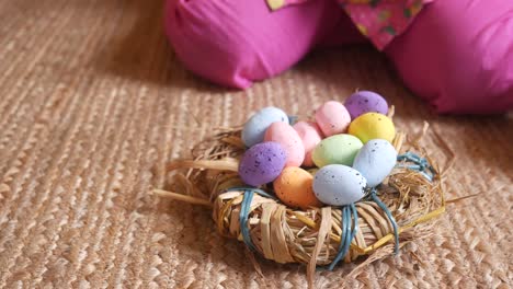 huevos de pascua en un nido de paja con un niño en pantalones rosados