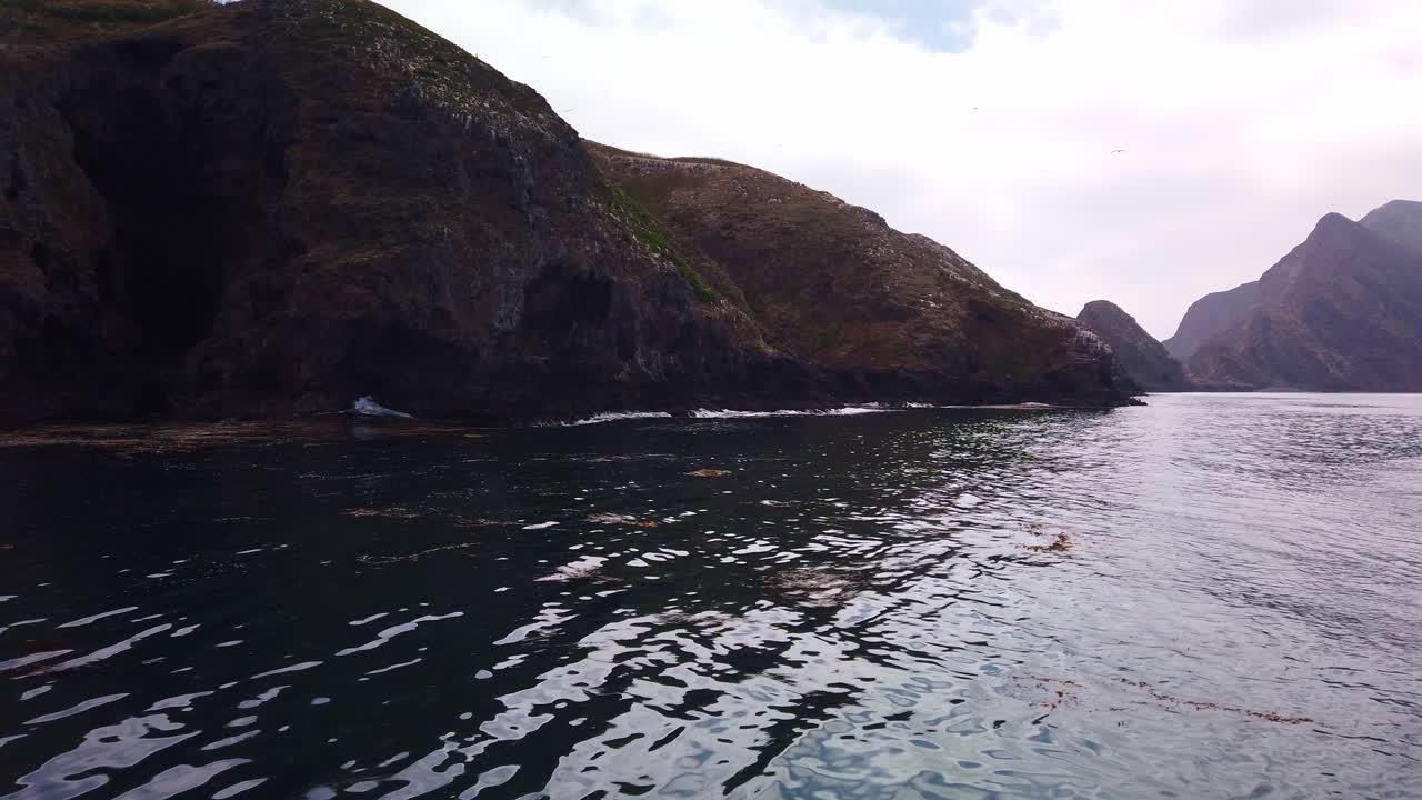 태평양의 채널 제도 국립공원에 있는 아나카파 섬 중앙 해안선을 따라 늘어선 견고한 바다 동굴의 움직이는 보트에서 짐벌 클로즈업 샷