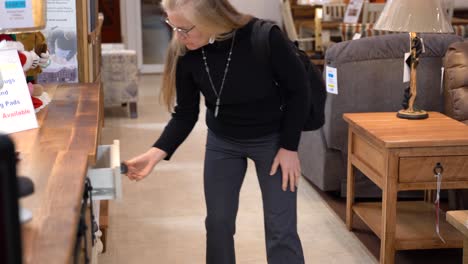 pretty mature blonde woman looking at dining room cabinets in a furniture store