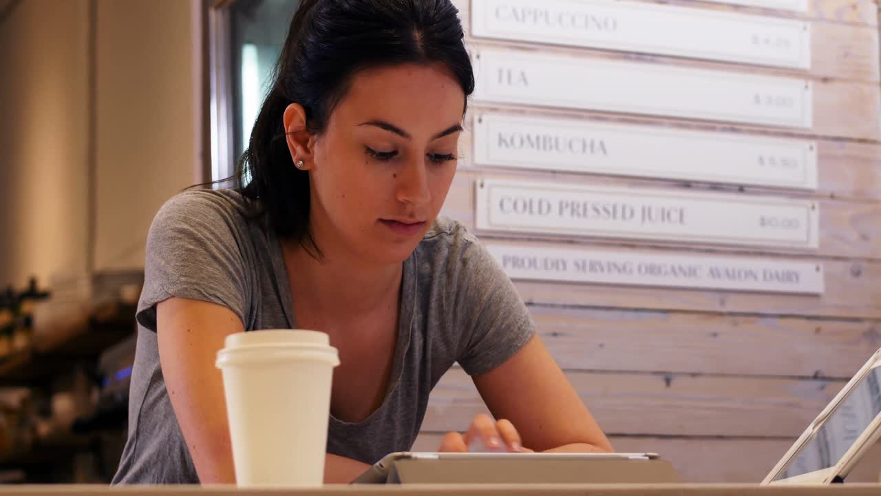 Donna con una tazza di caffè che usa un tablet digitale sul tavolo