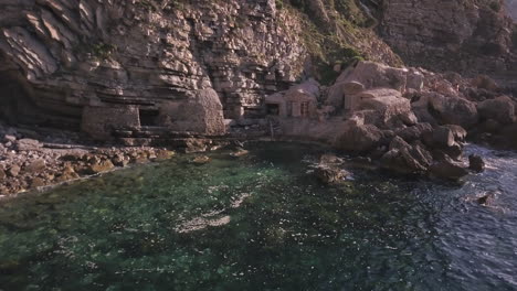 intriguing hidden fisherman's huts on the rocky water's edge ibiza, drone