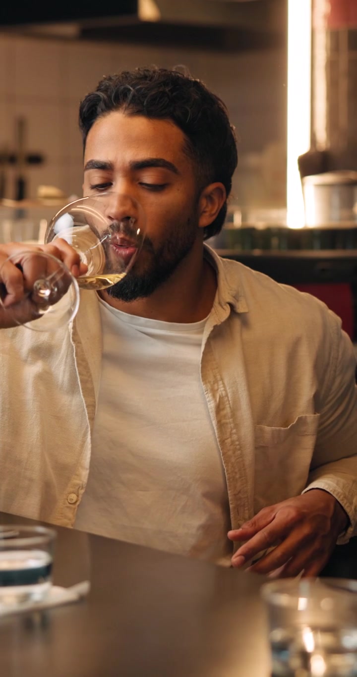 Young Man Toasting and Drinking White Wine at a Restaurant