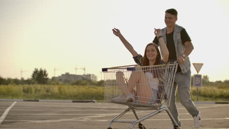 young friends having fun on shopping trolleys. multiethnic young people racing on shopping cart. slow motion