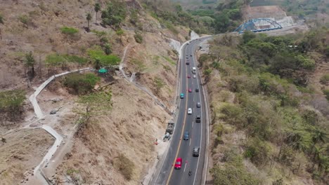 aerial drone view: a winding highway cutting through arid hilly terrain