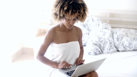 Happy-woman-using-laptop-on-bed.