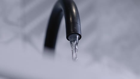 seen from below a black tap is turned on and water quickly gushes out.