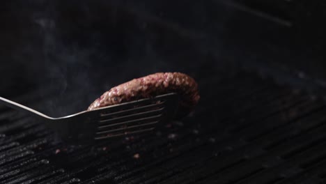 burger patty being flipped and grilled with flames