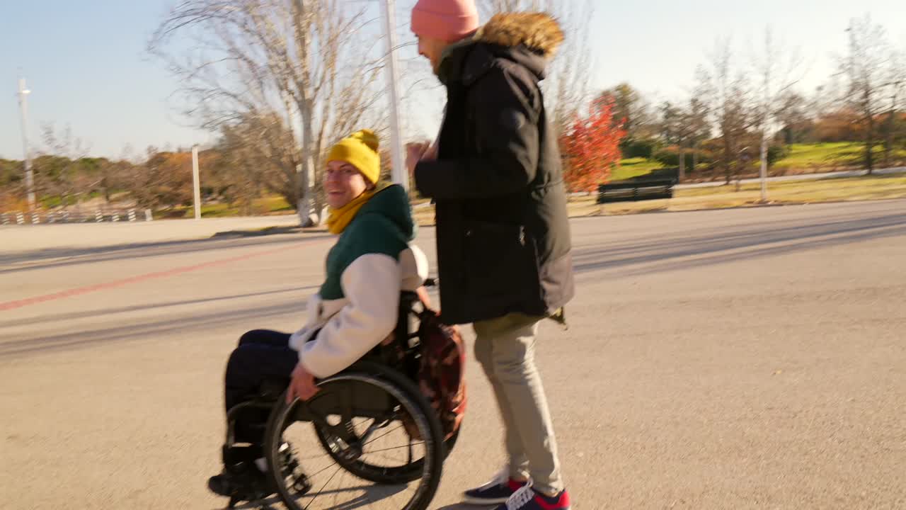 Man Pushing Woman in Wheelchair in Autumn Park