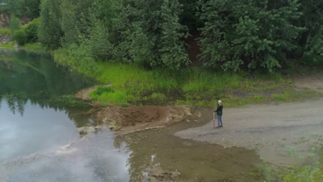 Aerial-view-of-mature-woman-standing-near-a-lake-4k