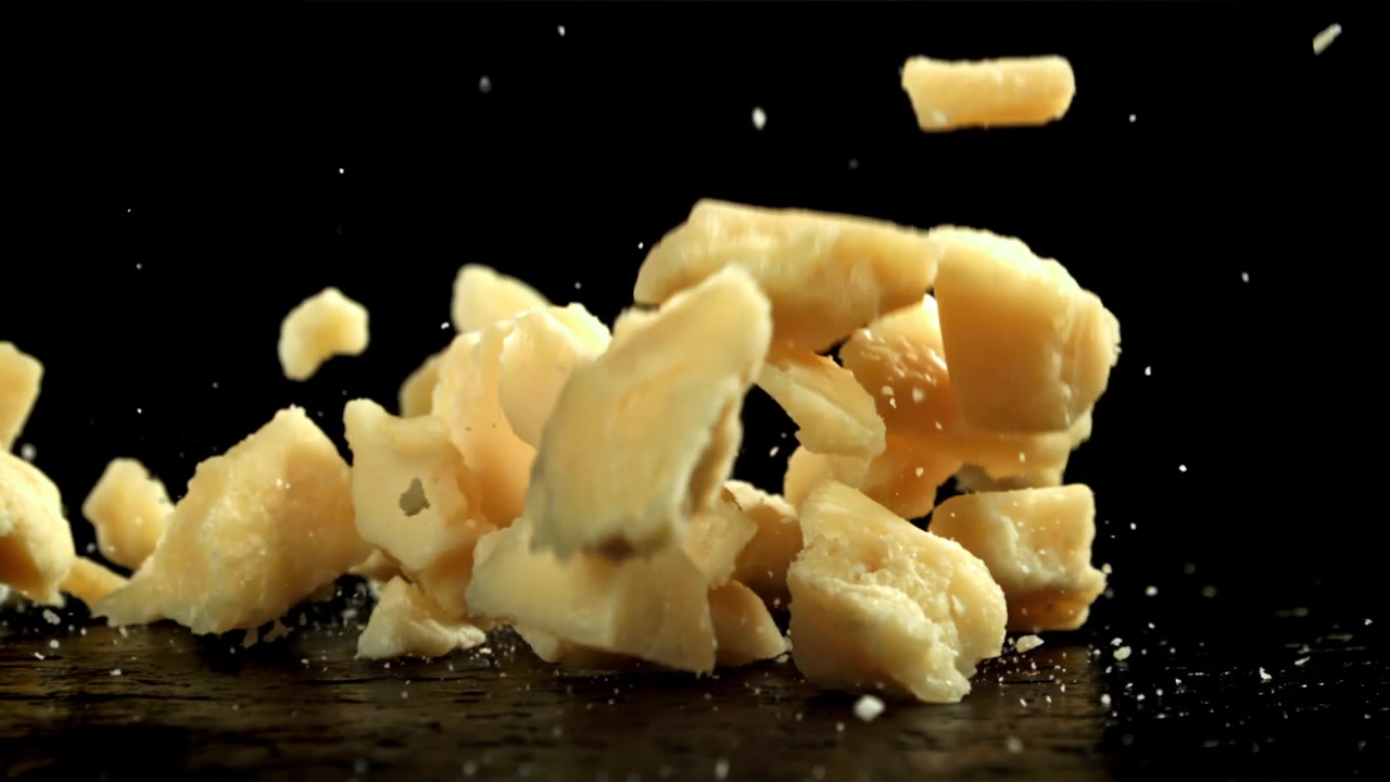 Slow Motion of Parmesan Cheese Shards Falling on Black Background