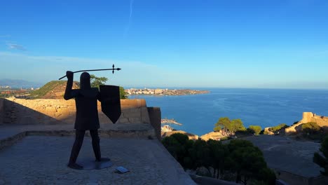 Castillo-De-Santa-Bárbara-En-Alicante,-España,-Estatua-Con-El-Mar-Balear-De-Fondo-Durante-El-Día-En-4k-30-Fps