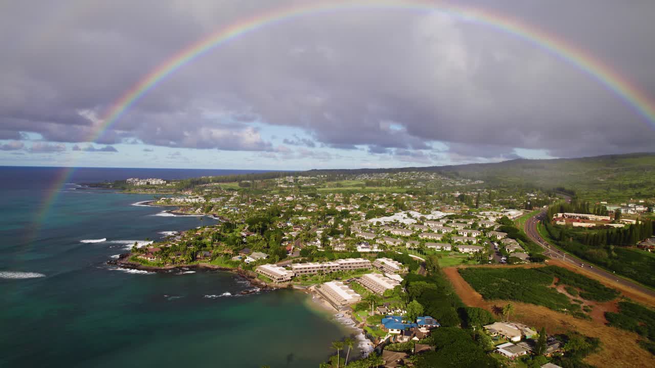 hermosos arcos de arco iris perfectos desde el océano claro hasta las verdes y vibrantes montañas exuberantes sobre las casas en la costa