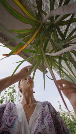 woman admiring a plant on a balcony